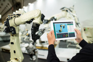 iot industry 4.0 concept,industrial engineer using software (augmented, virtual reality) in tablet to monitoring machine in real time.Smart factory use Automation robot arm in automotive manufacturing
